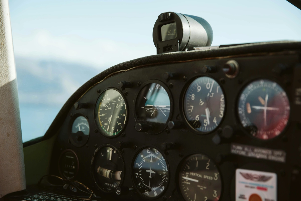 Closeup of vintage instrument panel showing altimeter, compass and airspeed dials.