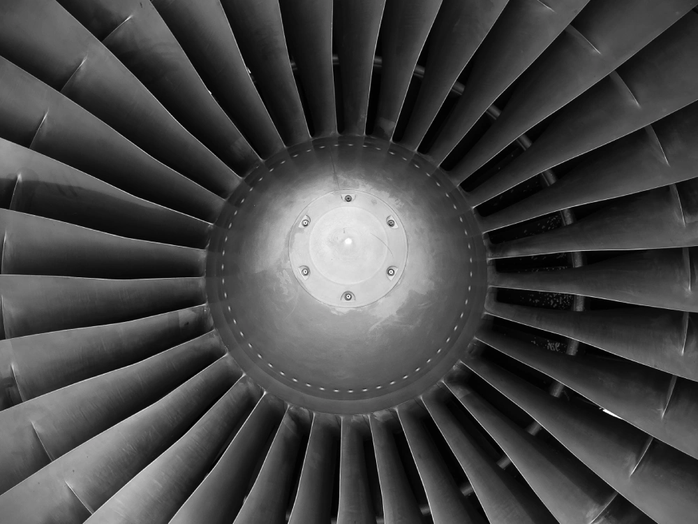 Close-up of jet engine turbine blades forming symmetrical radial pattern.